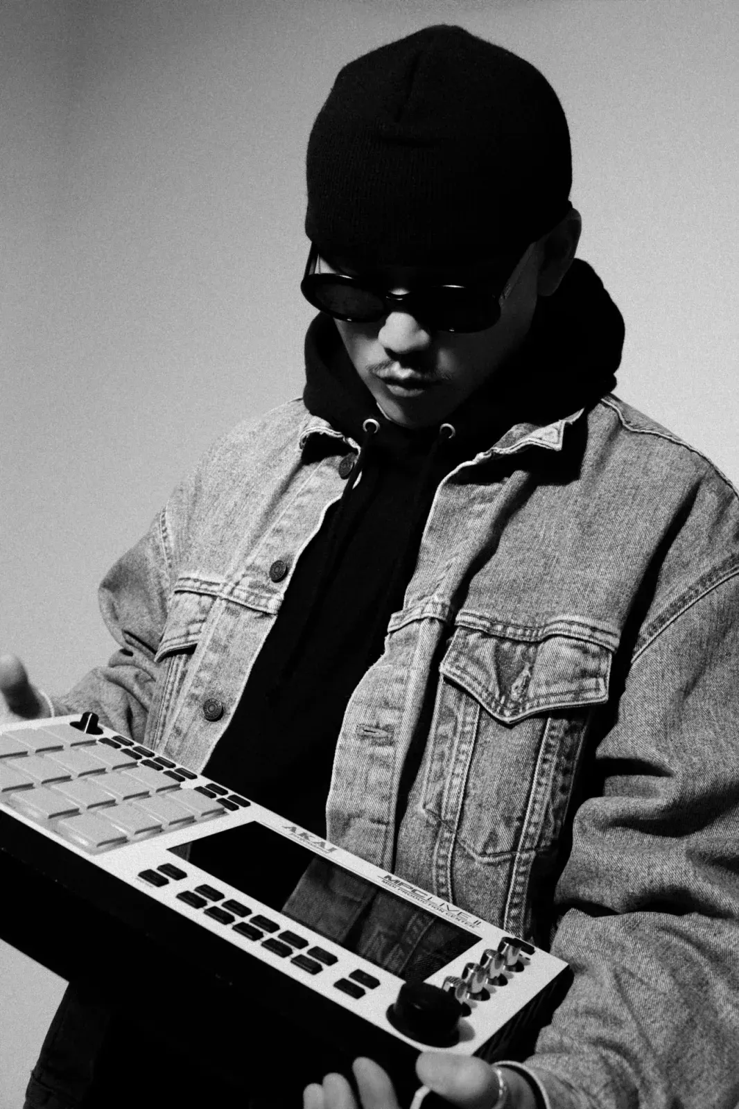 검은 모자와 선글라스를 쓰고 샘플러를 든 DJ POOL의 흑백 사진