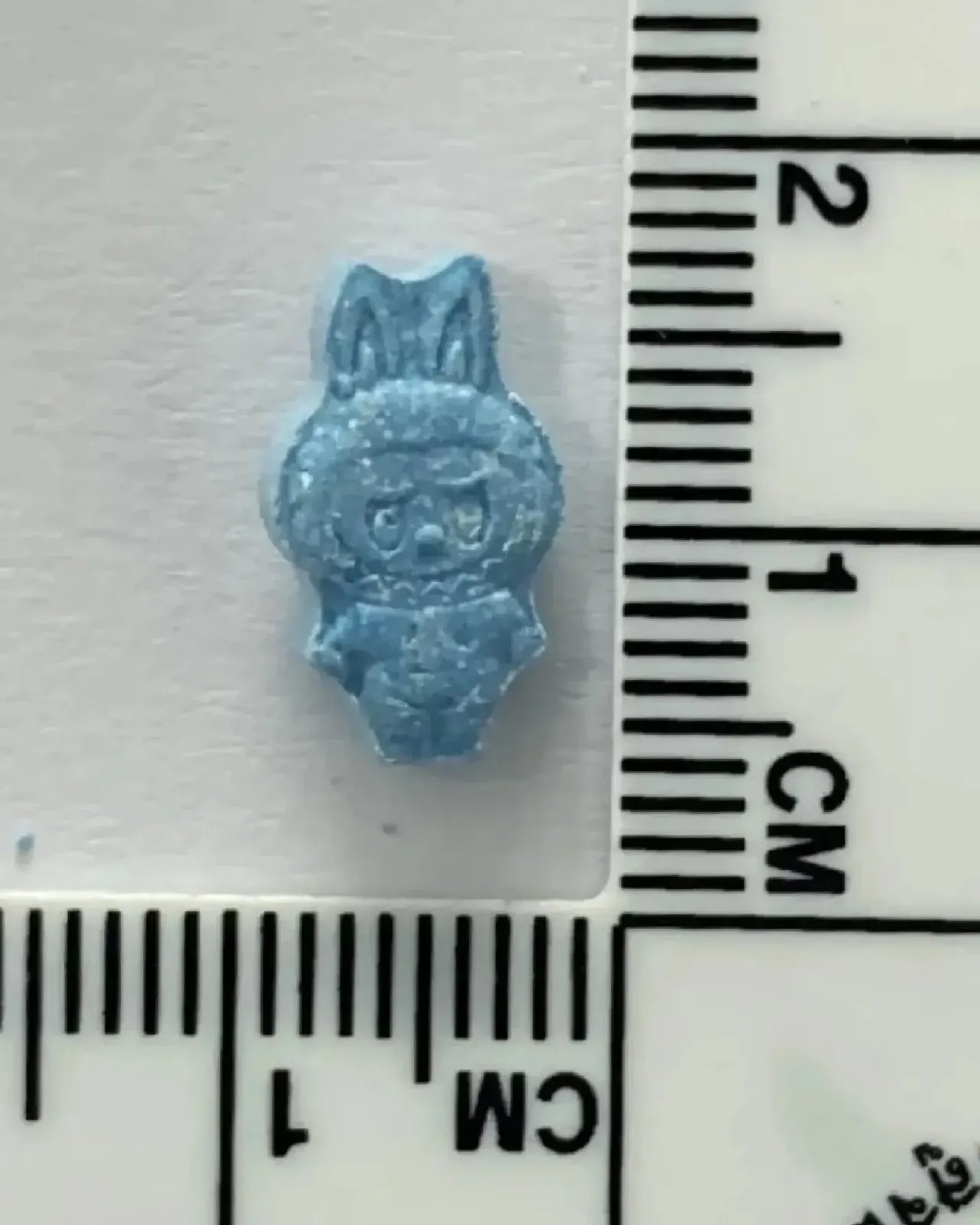 자 위에 놓인 파란 라부부 모양 알약. 길이 1cm 남짓